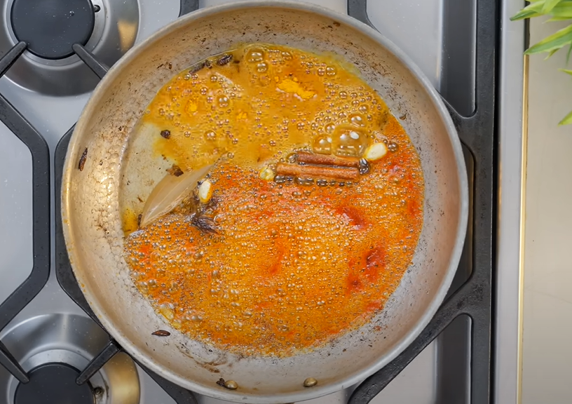 Mixing Kashmiri red chili and turmeric powder for rich paneer flavor