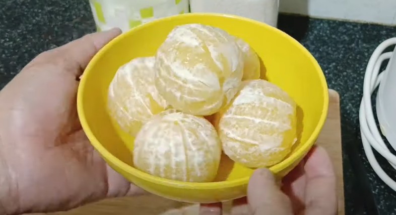 साफ-सुथरी मौसमी को छीलते हुए, मौसमी का जूस बनाने का पहला स्टेप