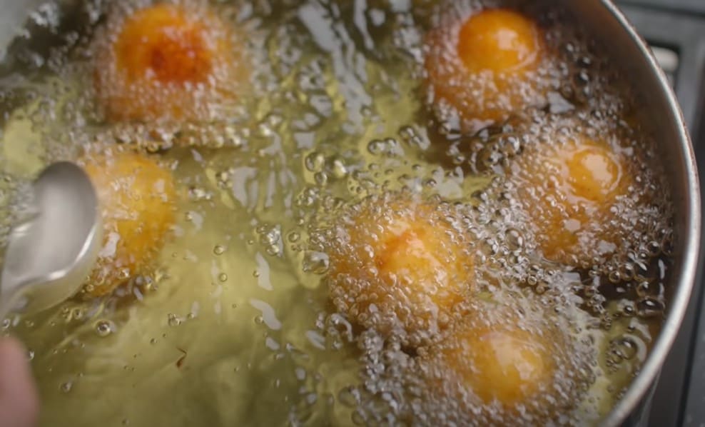 कोफ्ते में फिलिंग भरकर गोल बनाते और धीमी आँच पर सुनहरा फ्राई करते हुए