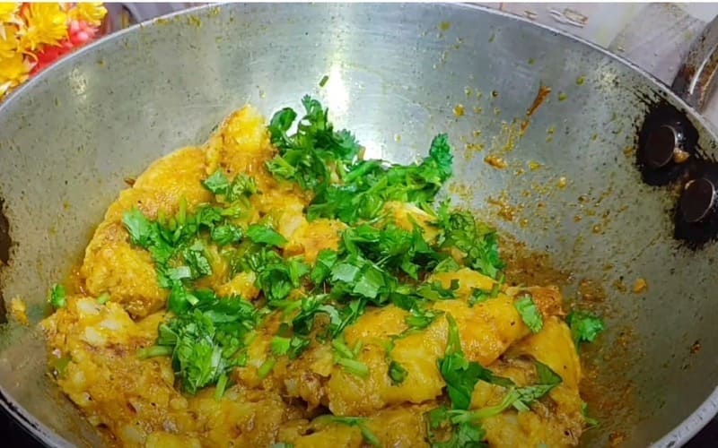 मैश किए हुए आलू को मसाले में मिलाकर हरा धनिया डालते और भूनते हुए – आलू कचोरी की स्टफिंग तैयार करते समय