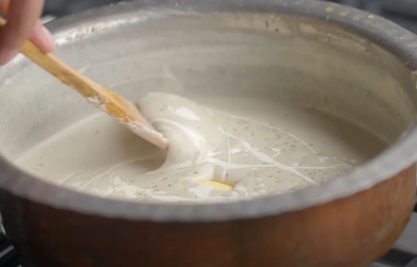 मसाले डालकर मलाई कोफ्ता ग्रेवी पकाते और छानकर उसमें बटर और मलाई मिलाते हुए