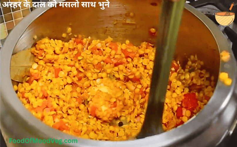 अरहर दाल को मसालों के साथ कुकर में मीडियम आंच पर भूनते हुए