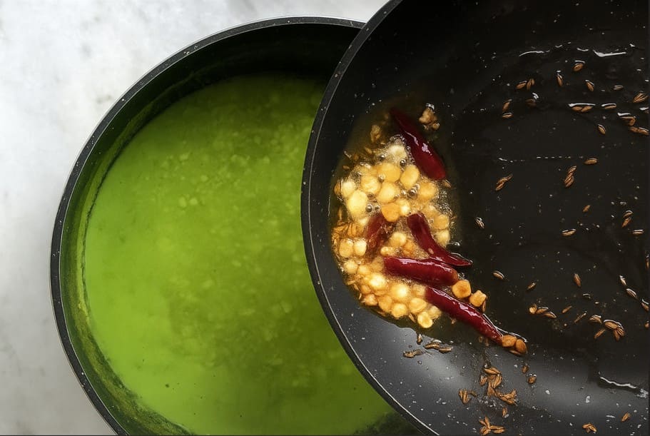 घी में करी पत्ता, हींग, लाल मिर्च, अदरक और लहसुन का तड़का तैयार करके दाल में डाला जा रहा है