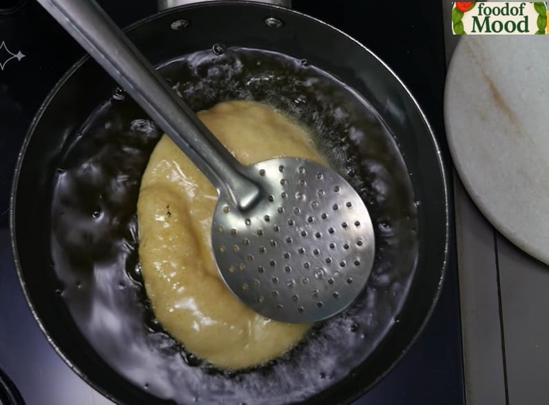 भटूरे को गरम तेल में डालकर हल्के हाथों से दबाते हुए फुलाते हुए – कुरकुरा और फूला हुआ भटूरा बनाने की प्रक्रिया